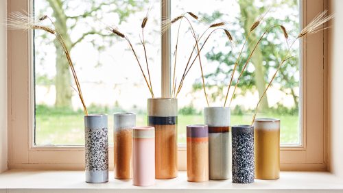 Getreidehalme in kunstvollen Keramik-Vasen auf einer Fensterbank