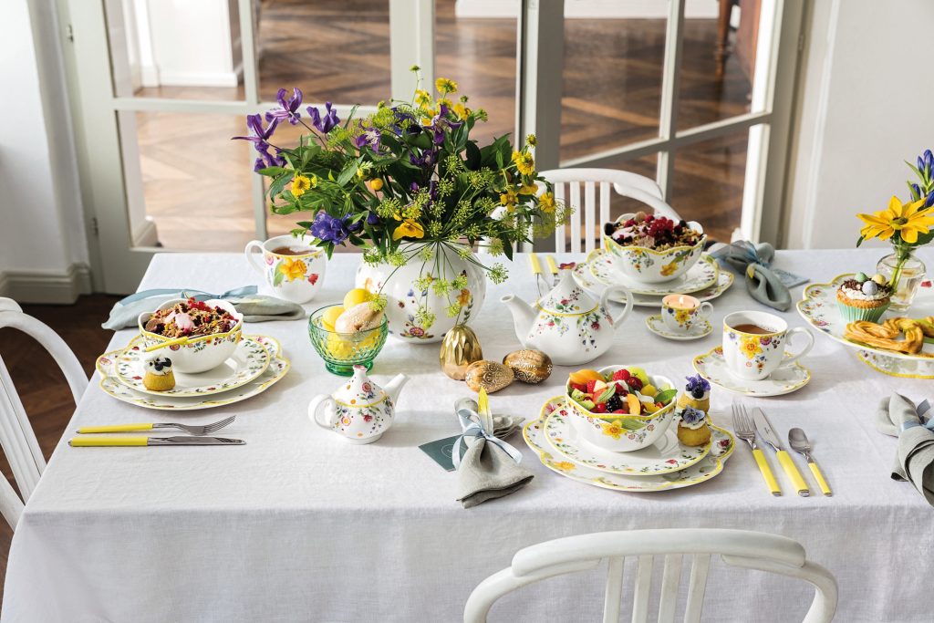 Ein hübsch gedeckter Ostertisch mit buntem Geschirr, einem großen Blumenstrauß und frühlingshaften Farben