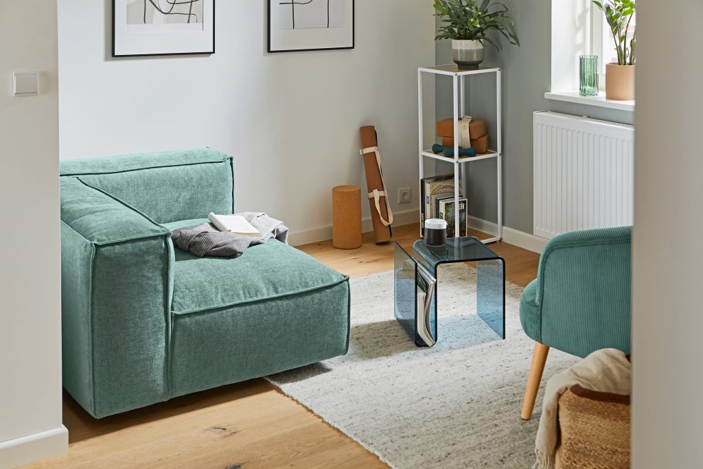 Entspannte Wohnzimmersituation mit kleiner Eck-Couch und daneben der Acryl Hocker von Tchibo.